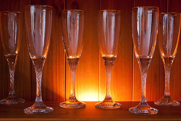 Image showing Empty wine glasses on a wooden shelf