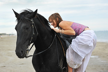 Image showing woman mount a  horse on the beach