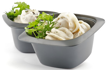 Image showing Meat pelmeni with sour cream and greens in black bowls