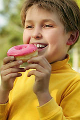 Image showing Child eating a pink doughnut