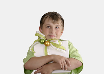 Image showing Child holding a wrapped present and thoughtfully looking up