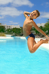 Image showing boy jumping into the pool smiling 