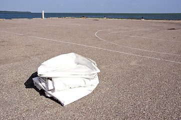 Image showing Yacht fabric cover lying on concrete marina ground 