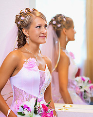 Image showing Beautiful bride in a pink dress near the mirror