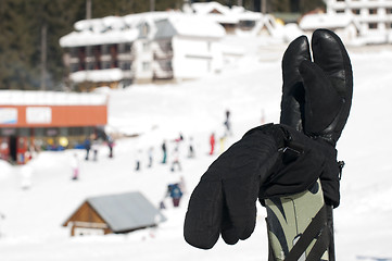 Image showing Ski gloves and sticks. Winter tourists on the background