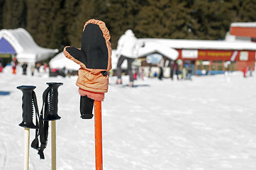 Image showing Ski gloves and sticks. Winter tourists on the background