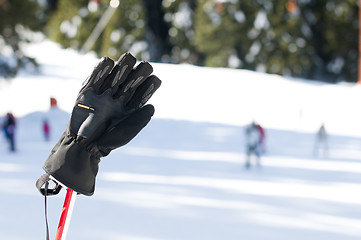 Image showing Ski gloves and sticks. Winter tourists on the background