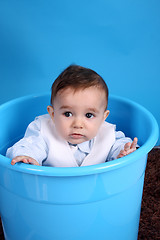 Image showing Portrait of a happy baby boy on blue bucket isolated on blue bac