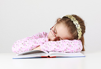 Image showing Tired schoolgirl sleeping on book