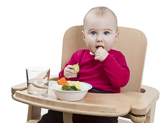 Image showing young child eating in high chair