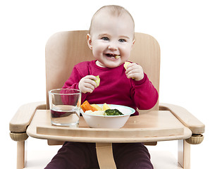 Image showing young child eating in high chair