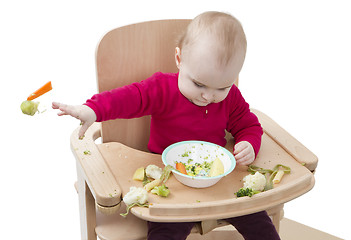 Image showing young child eating in high chair