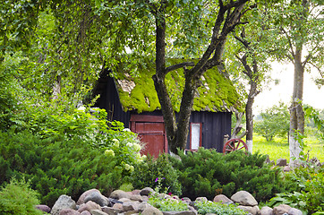 Image showing garden house mossy roof plants flowers background 