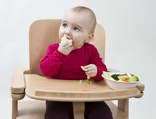 Image showing young child eating in high chair