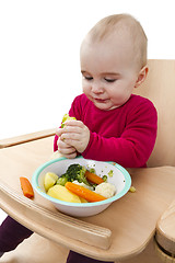 Image showing young child eating in high chair