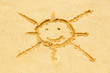 Image showing Smiling sun drawn on a sandy beach