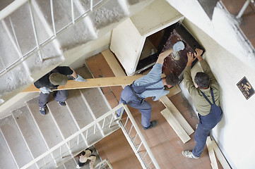 Image showing Workers move the safe on a lstaircase