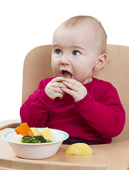 Image showing young child eating in high chair