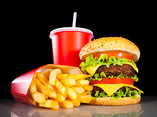 Image showing Tasty hamburger and french fries on a dark