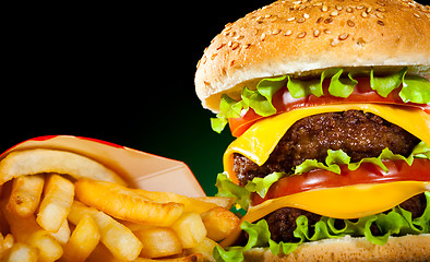 Image showing Tasty hamburger and french fries on a dark