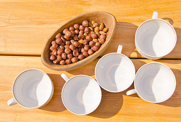 Image showing hazelnuts pack in wooden dish cups placed on table 