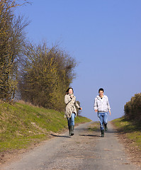 Image showing Couple of young people walking in the campaign in spring