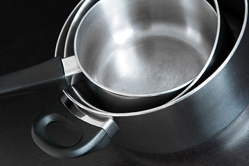 Image showing Metal saucepans on dark background