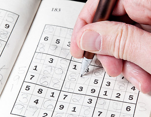 Image showing Man hand holding pencil on sudoku puzzle
