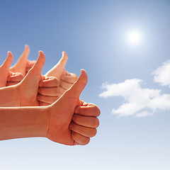 Image showing thumbs up on background of blue sky and white clouds