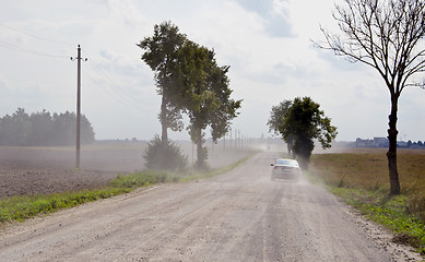 Image showing Dusty rural gravel road between farm fields 