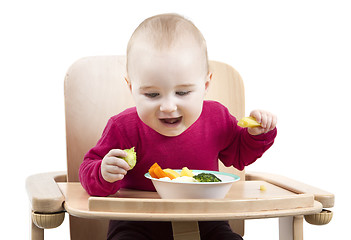 Image showing young child eating in high chair