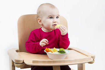 Image showing young child eating in high chair