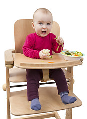 Image showing young child eating in high chair