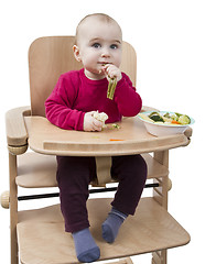 Image showing young child eating in high chair