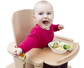 Image showing young child eating in high chair