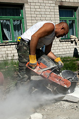 Image showing Worker with industrial saw cutting a concrete block