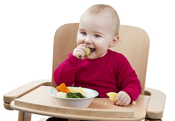 Image showing young child eating in high chair