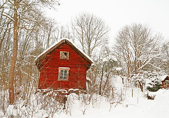 Image showing Very old red wooden house in a snowy forest