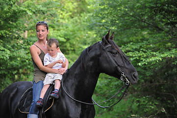 Image showing mother, son and black horse