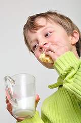 Image showing child eating cake and drinking milk