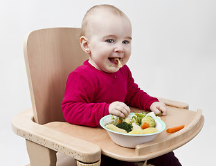 Image showing young child eating in high chair