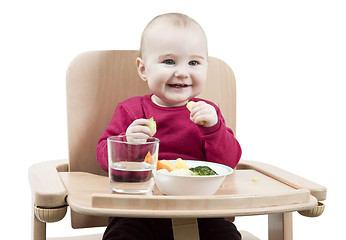 Image showing young child eating in high chair