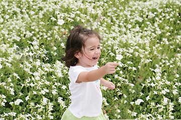 Image showing Baby girl happy in a garden of flowers