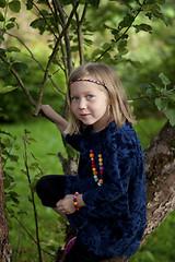 Image showing Little girl sitting on a branch of an apple tree