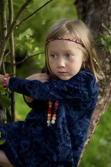 Image showing Little girl sitting on a branch of an apple tree