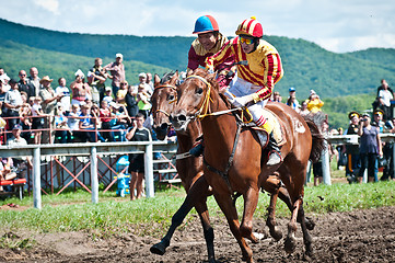 Image showing Riders finish a race waving whips