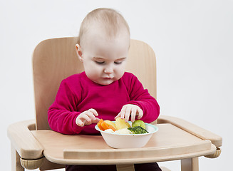 Image showing young child eating in high chair