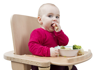 Image showing young child eating in high chair