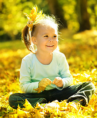 Image showing Cute little girl is playing with leaves in park