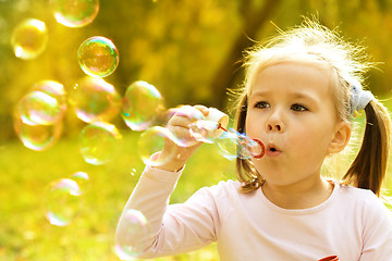 Image showing Little girl is blowing a soap bubbles